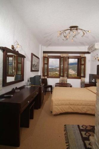 a bedroom with two beds and a desk and a mirror at Hotel Taxiarches in Aristi