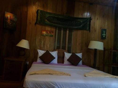 a bedroom with a bed with two lamps and avertisement at Tree Top Eco-Lodge in Banlung