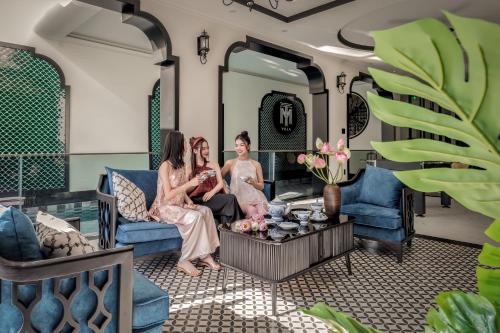 T-Maison Indochine Vung Tau Villa near beach FREE pool, billiards, karaoke في فنغ تاو: مجموعة من ثلاث نساء يجلسون في غرفة المعيشة