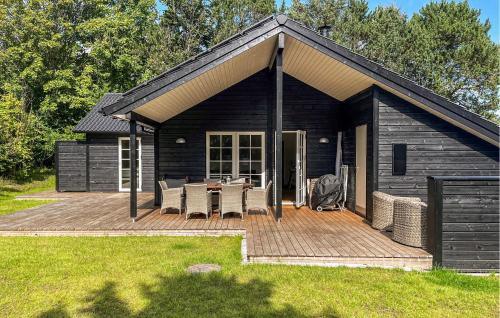 a house with a deck with a table and chairs at 3 Bedroom Awesome Home In Tisvildeleje in Tisvildeleje