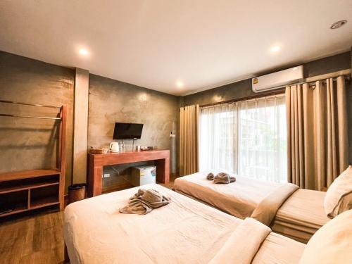 Cette chambre comprend deux lits et une télévision. dans l'établissement BOSS HOTEL CHIANGMAl, à Chiang Mai