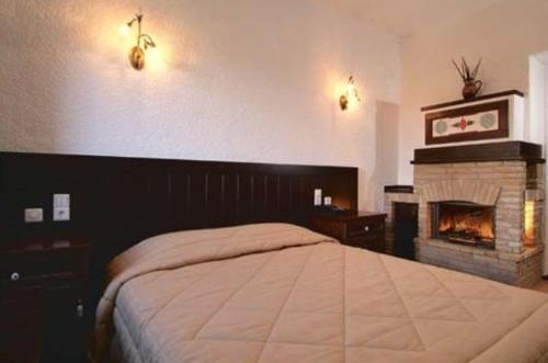 a bedroom with a large bed and a fireplace at Hotel Taxiarches in Aristi