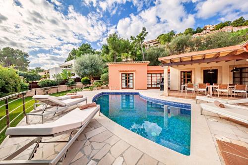 a swimming pool with lounge chairs and a house at Beach Villa Margot in Port de Pollensa