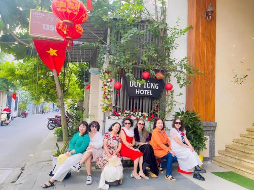 un grupo de mujeres sentadas en un banco frente a un edificio en Duy Tung Hotel Da Nang en Da Nang