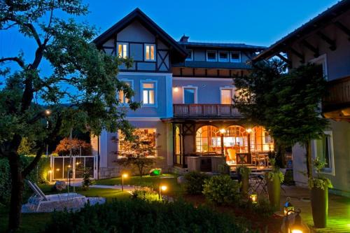 a large blue house with lights in the yard at Vila Alice Bled - Adults only in Bled