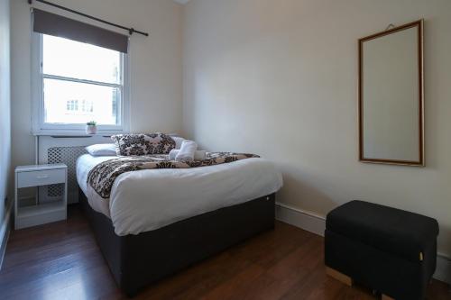a bedroom with a bed with a mirror and a window at Queensway Flat by DC London Rooms in London