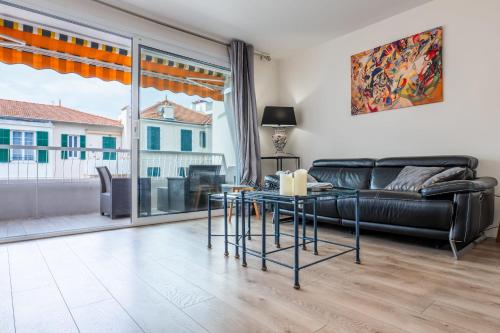 un salon avec un canapé en cuir noir et une table dans l'établissement 2-room apartment with terrace close to the center, à Cannes