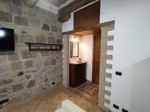 a room with a stone wall and a bathroom with a sink at Dimora de' Canulei in Bolsena