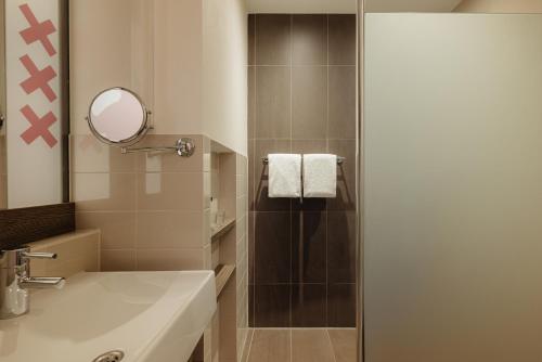 uma casa de banho com um chuveiro, um lavatório e um espelho. em The Manor Amsterdam em Amsterdã
