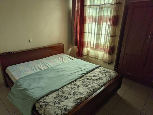 a small bed in a room with a window at Home in kigali in Kigali