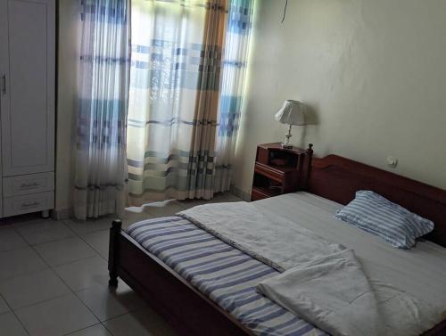 a bedroom with a bed and a table and curtains at Home in kigali in Kigali