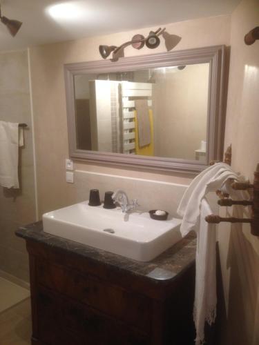 ein Badezimmer mit einem Waschbecken und einem großen Spiegel in der Unterkunft la Grange de Chérence in Chérence