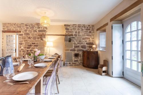 une salle à manger avec une table et un mur en pierre dans l'établissement La Ville Bourse - Charmante villa à Erquy, à Erquy