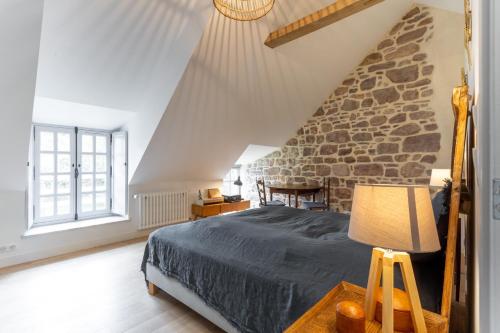 a bedroom with a bed and a stone wall at La Ville Bourse - Charmante villa à Erquy in Erquy