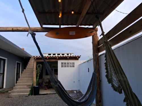 a hammock in front of a house with a surfboard at Pousada Luz Beira mar in Tramandaí