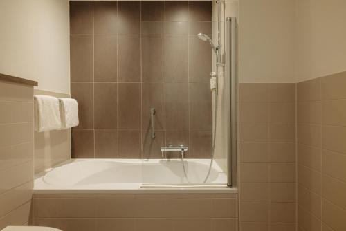 a bathroom with a bath tub with a shower at The Manor Amsterdam in Amsterdam