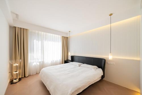 a bedroom with a white bed and a large window at Shanghai Downtown Yi Du B&B - Near Hongqiao Station and Jiaotong University in Shanghai