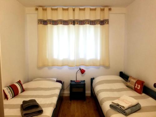 two beds in a room with a window at Villa Kerjoa - T8 - grand jardin in Arcachon