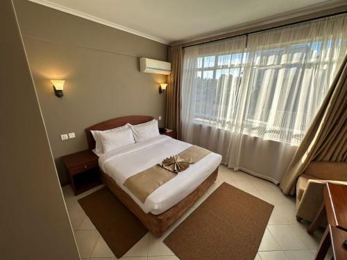 a bedroom with a bed and a large window at Comfort Eland Hotel in Arusha