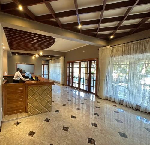 a man standing at a counter in a large room at Comfort Eland Hotel in Arusha