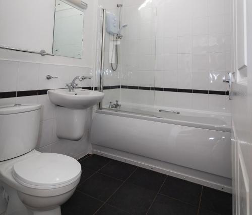 a white bathroom with a toilet and a sink at Toes Rock Sandy Haven in Herbrandston