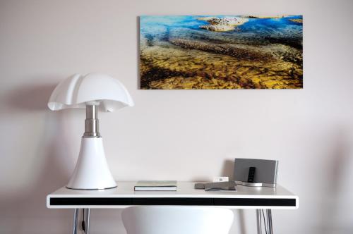 a table with a lamp and a painting on the wall at La Villa Calvi in Calvi