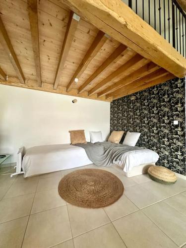 a bedroom with a large bed and a wooden ceiling at Joli Mas duplex piscine parking in Mudaison