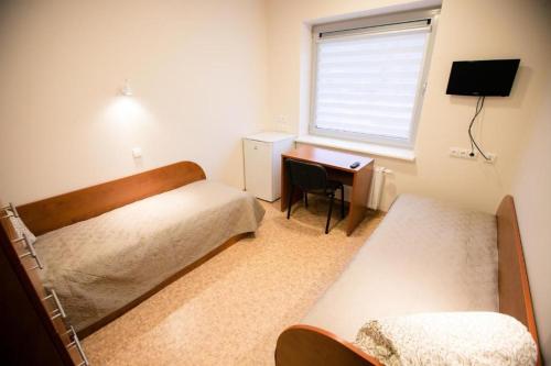 a bedroom with two beds and a desk and a window at Alytaus sporto viešbutis in Alytus