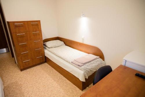niewielka sypialnia z łóżkiem i komodą w obiekcie Alytaus sporto viešbutis w Olicie