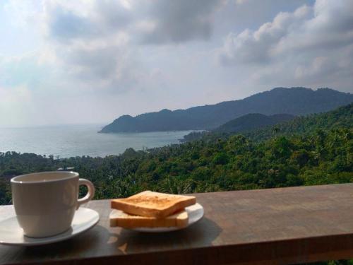 a cup of coffee and some bread on a table at Ozone Hill Panoramic Residence Thong Nai Pan Beach in Thong Nai Pan Noi