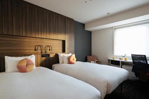 a hotel room with two beds and a desk at OMO3 Sapporo Susukino by Hoshino Resorts in Sapporo