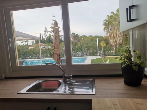 um lavatório de cozinha com vista para uma piscina através de uma janela em Suit Garden Huelva em Aljaraque