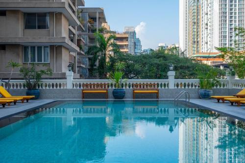 uma piscina com bancos e edifícios em Boulevard Hotel Bangkok Sukhumvit em Banguecoque