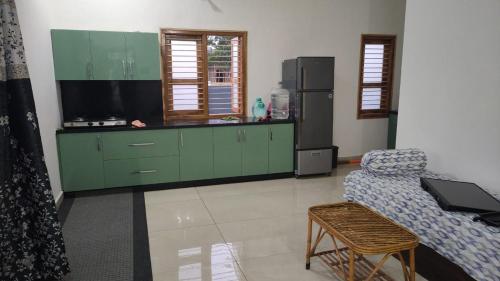 eine Küche mit grünen Schränken und einem Kühlschrank in der Unterkunft R S COMFORTS in Mysore