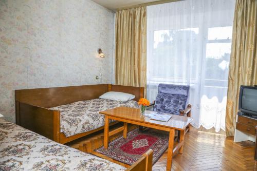 a bedroom with a bed and a table and a tv at Dnepropetrovsk Hotel in Dnipro