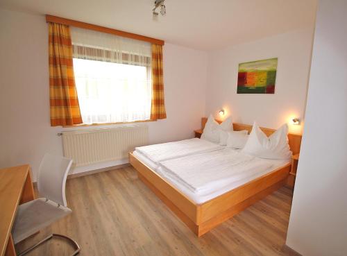 a bedroom with a large white bed and a window at Ferienwohnung "Haus Falle" in Schiefling am See