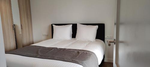1 dormitorio con 1 cama con sábanas y almohadas blancas en Antonius Hoeve Chalets en Oudenbosch