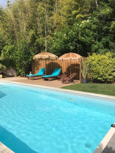 - une piscine avec 2 chaises bleues et des parasols dans l'établissement Gîte de Fenouil Le Cocon, à Civrac-de-Blaye
