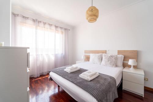 a white bedroom with a bed with two towels on it at Beach Flat by House and People in Viana do Castelo