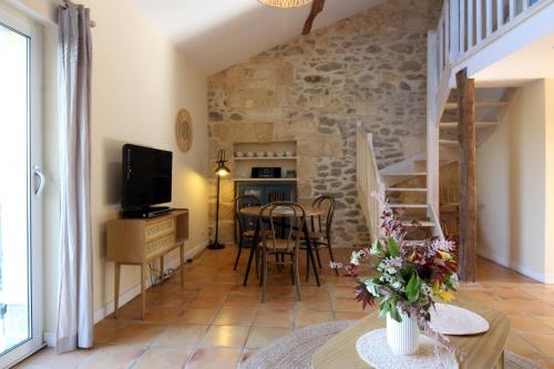 a living room with a table and chairs and a tv at Gîte de Fenouil - Le Cocon, 2 pers, dans parc avec piscine - 3 étoiles in Civrac-de-Blaye