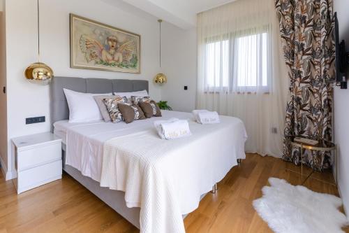 a bedroom with a large white bed and a window at Villa Lux ZadarVillas in Zemuniki