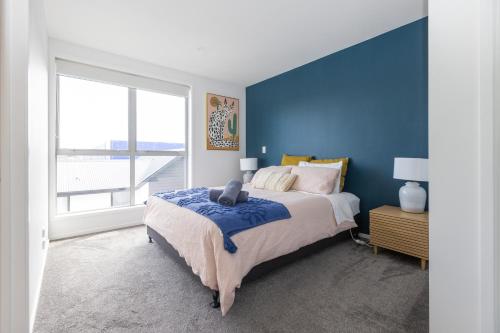 a blue bedroom with a bed and a large window at stylish and comfort in CBD in Christchurch