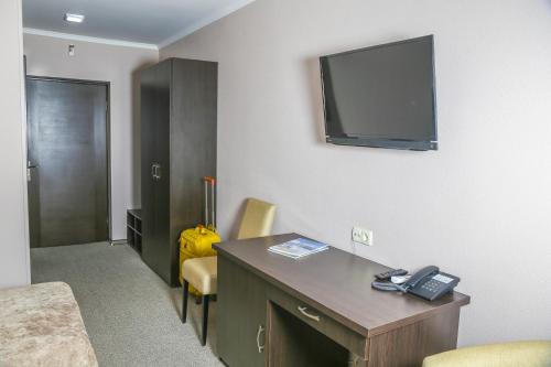 a hotel room with a desk and a tv on the wall at Dnepropetrovsk Hotel in Dnipro