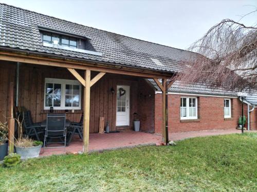 a house with a covered porch with a patio at Ferienwohnung Auszeit 65354 in Moormerland