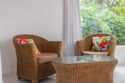 two wicker chairs and a glass table in a room at Bella Beach Bungalows in Rarotonga