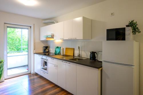 uma cozinha com armários brancos e um frigorífico branco em Moderne Ferienwohnung / Monteurswohnung mit 8 Betten in Marburg em Marburgo