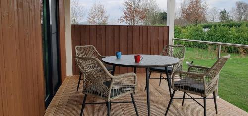 a table and four chairs on a porch with a view of a yard at Antonius Hoeve Chalets in Oudenbosch