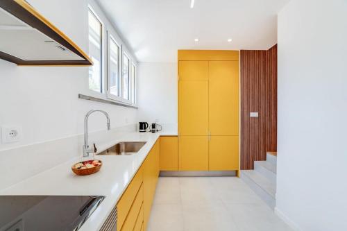 eine Küche mit einem Waschbecken und einer gelben Tür in der Unterkunft Cozy Coastal Getaway 3BR Apartment in Estoril in Estoril