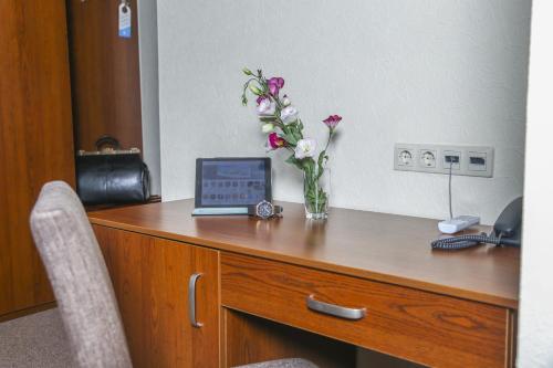 a desk with a vase of flowers and a laptop on it at Dnepropetrovsk Hotel in Dnipro