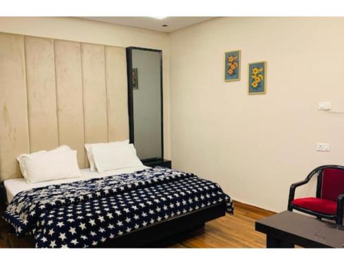 una camera con letto e sedia rossa di Hotel Alpine, Kurukshetra a Kurukshetra